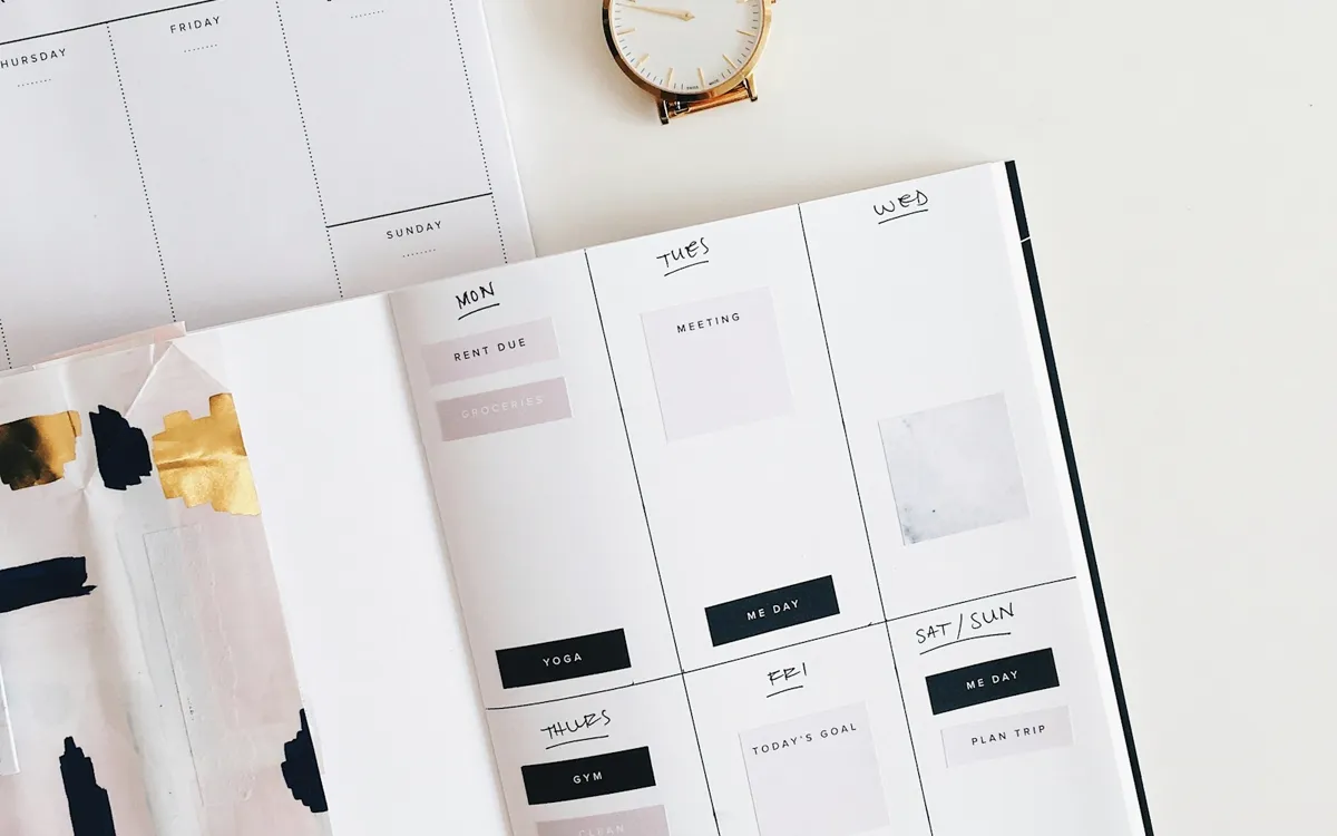 A weekly planner with a gold wristwatch resting on top